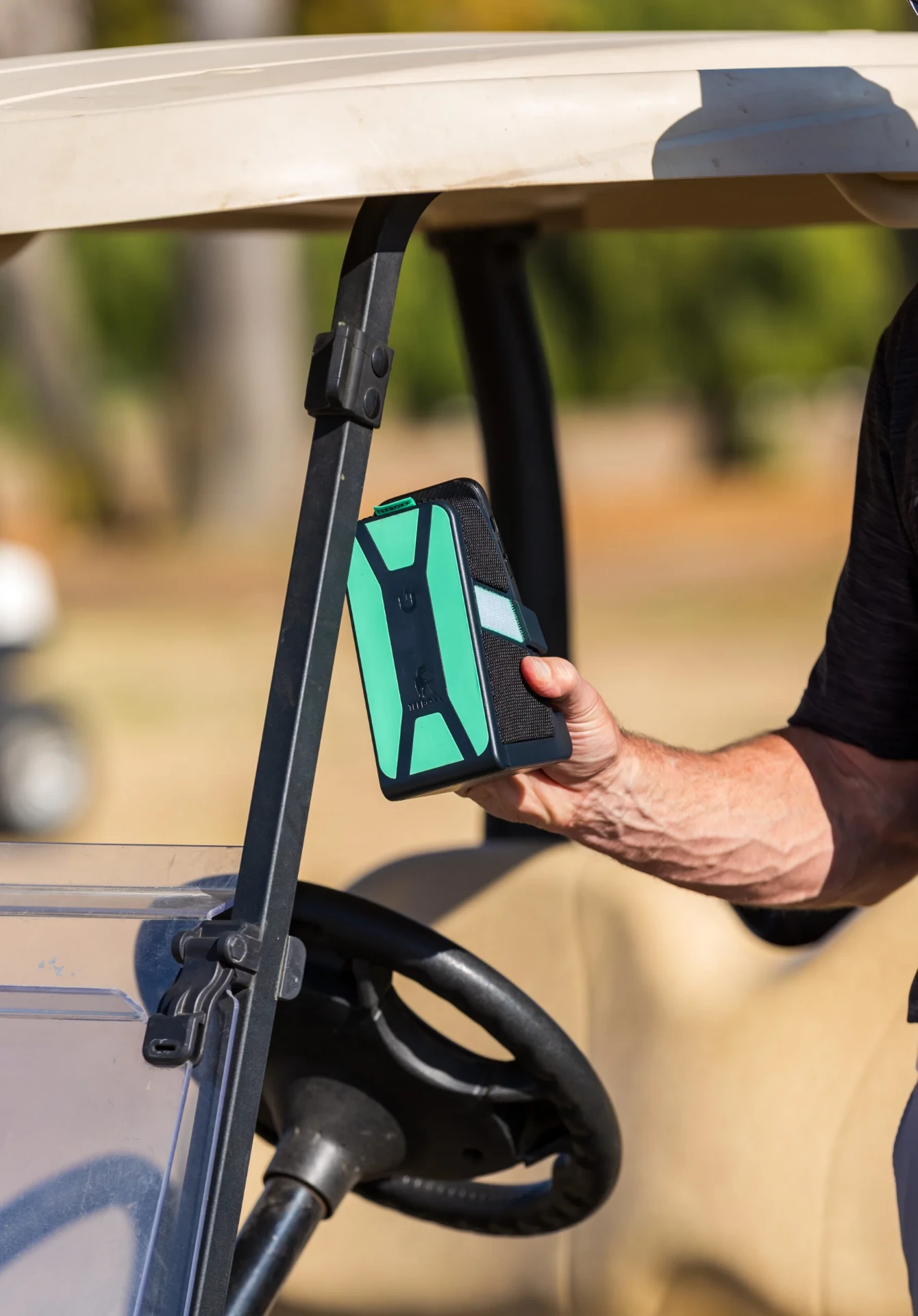 Golfer attaching the mint and black TeeBoxx to a golf cart frame