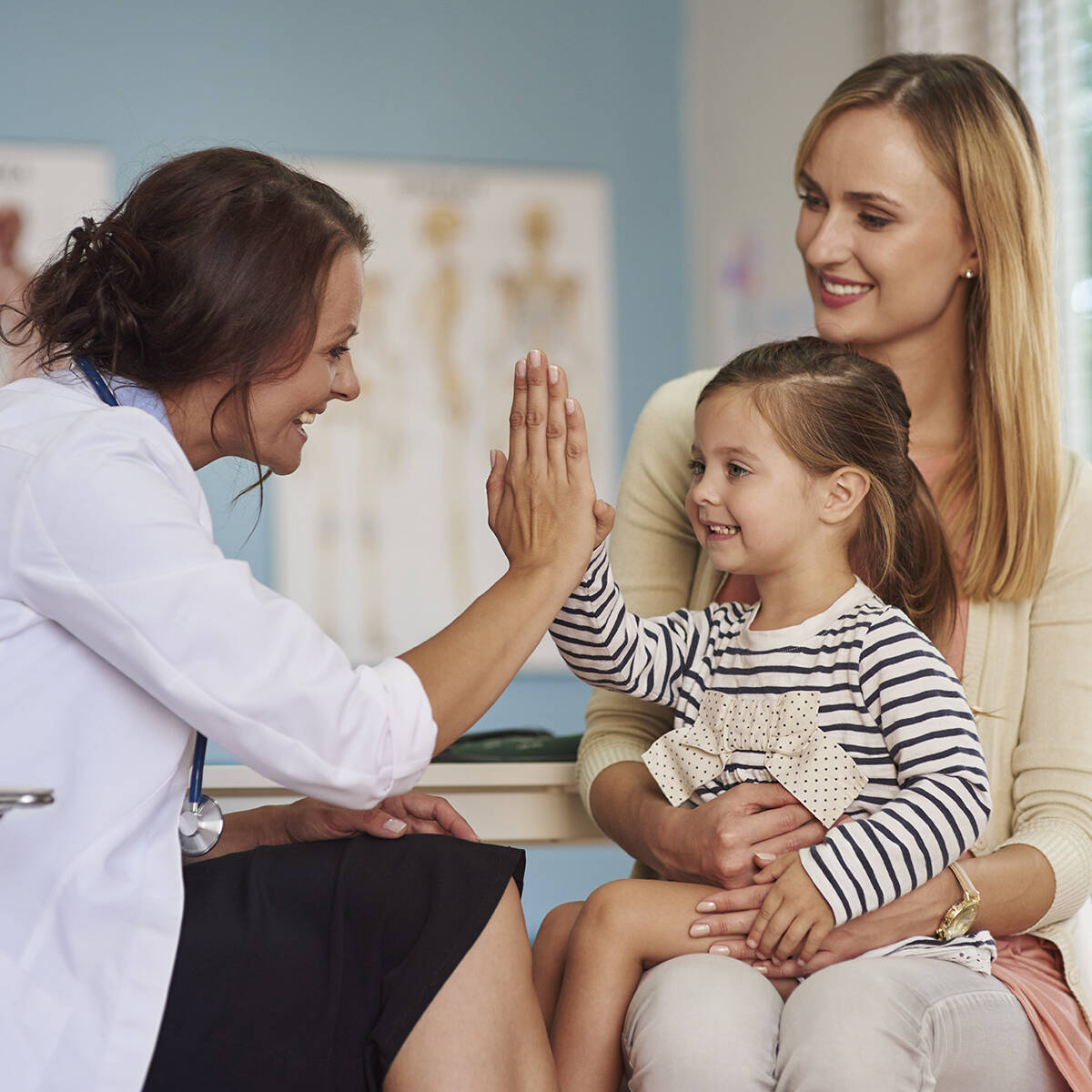 Pediatrician high-fiving a young patient during a family visit
