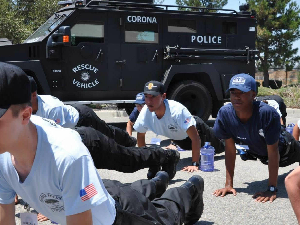 Corona Police Explorers doing push-ups in front of a department rescue vehicle