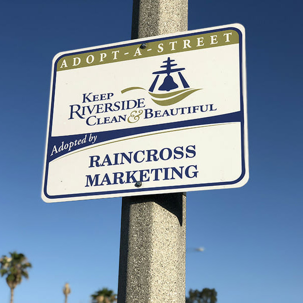 An Adopt-A-Street sign for the Keep Riverside Clean and Beautiful program reading adopted by Raincross Marketing