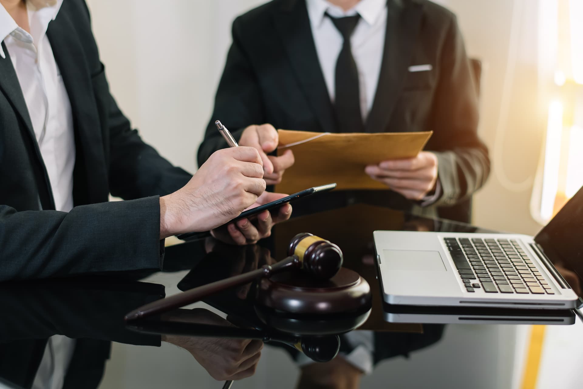 Two attorneys reviewing a case document at a desk with a gavel and laptop