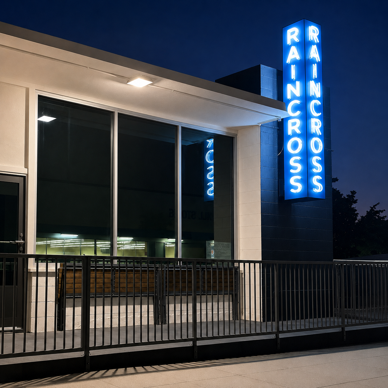 The Raincross office at dusk, with the blue neon Raincross sign lit above the entrance