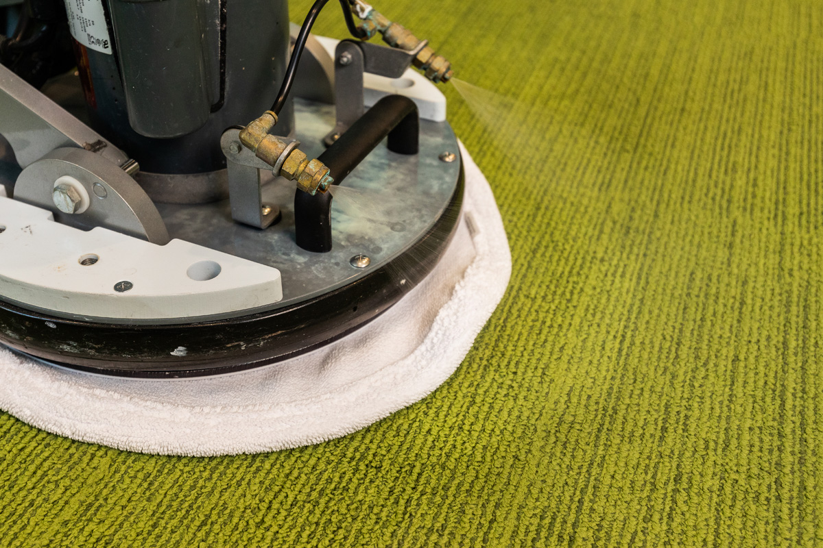 Close-up of an OctoClean interim carpet cleaning machine treating green office carpet